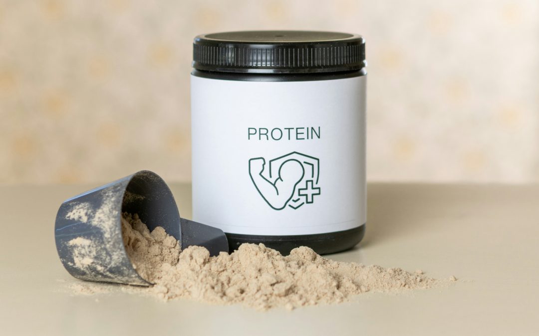 Generic black protein powder container with black protein scoop and loose protein powder on plain table surface